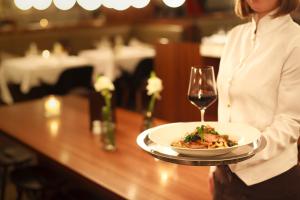 a woman holding a plate of food and a glass of wine at The Guesthouse Vienna in Vienna