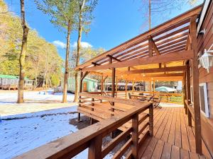 eine Holzterrasse mit Bänken auf einem Gebäude in der Unterkunft 森と湖の楽園ＷorkshopＣampＲesort in Fujikawaguchiko