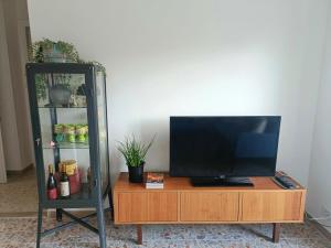 a television sitting on a wooden entertainment center at Casa Cocò - Appartamento al mare in Lido di Ostia