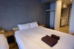 a large white bed with a brown towel on it at OPUS Haneda in Tokyo