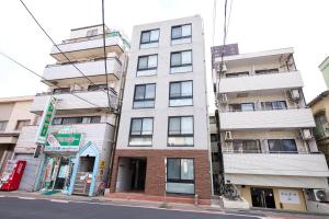 a tall white building on the side of a street at OPUS Haneda in Tokyo