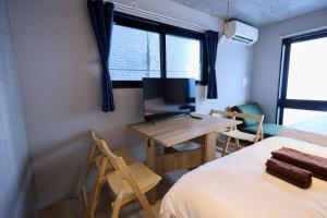 a room with two beds and a desk with a television at OPUS Haneda in Tokyo