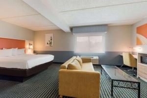 a hotel room with a bed and a couch at Baymont by Wyndham Westampton in Westampton Township