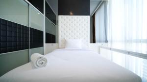 Una cama blanca grande en una habitación con ventana. en Spacious and Homey 2BR at The Via and The Vue Apartment By Travelio, en Surabaya