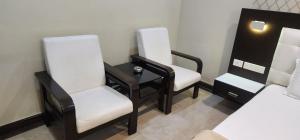 a room with three chairs and a table and a bed at SRI ViJETHA ROYAL in Rājahmundry