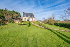 a house on a grassy hill with a statue in front at La Picardière - Piscine intérieure à Erquy in Erquy