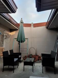 a patio with chairs and an umbrella and a table at Twin Nooks in Mabalacat +11 photos