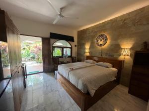 a bedroom with a bed and a stone wall at Catra homestay beach apartments in Candidasa