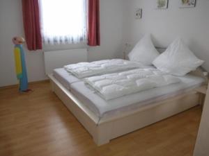 un lit blanc dans une chambre avec une fenêtre dans l'établissement Ferienhaus Nr 74, Kategorie Komfort L m Sauna, behindertenfreundlich, Feriendorf Hochbergle, Allgäu, à Bichel