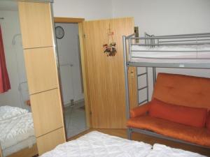 - une chambre avec des lits superposés, une chaise et un miroir dans l'établissement Ferienhaus Nr 74, Kategorie Komfort L m Sauna, behindertenfreundlich, Feriendorf Hochbergle, Allgäu, à Bichel