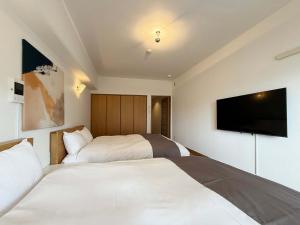 ein Hotelzimmer mit zwei Betten und einem Flachbildfernseher in der Unterkunft Grandeur by b hotel - Cozy 1BR Near Peace Park Quiet & Central Stay in Hiroshima