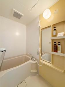 ein Badezimmer mit Badewanne und Spiegel in der Unterkunft Grandeur by b hotel - Cozy 1BR Near Peace Park Quiet & Central Stay in Hiroshima + 18 Fotos