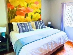 a bedroom with a bed with a flower painting on the wall at The Browns' Luxury Suites & Cottage in Dullstroom
