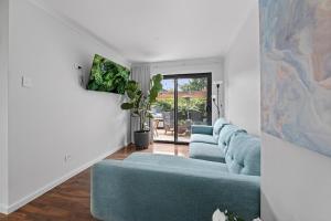 a living room with a blue couch and a staircase at 3 Bed Fully Renovated with Outdoor Fun in Watson