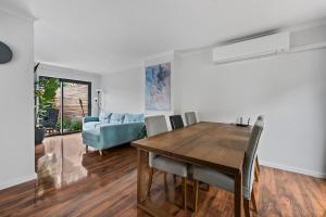 a dining room with a table and a blue couch at 3 Bed Fully Renovated with Outdoor Fun in Watson