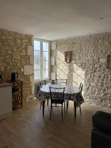 a dining room with a table and chairs and a stone wall at Écrin de Loire in Pouilly-sur-Loire
