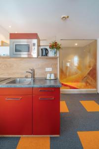 a red kitchen with a sink and a microwave at Altötting City Apartments in Altötting