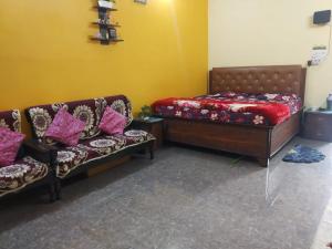 a bedroom with a bed and two chairs and a couch at Relish Homestay in Prayagraj
