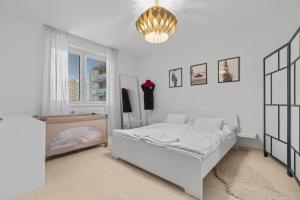 a white bedroom with a bed and a chandelier at AH Bosakova Elegant in Bratislava