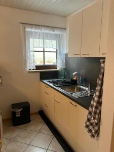 eine Küche mit einer Spüle, einem Herd und einem Fenster in der Unterkunft Birke 6 in Todtmoos