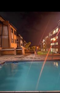 an empty swimming pool in front of buildings at night at Mordern Lil' Love Nest Loft in Midrand in Midrand