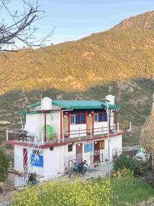 a house on a hill with a mountain in the background at Odyssey Stays Khirsu in Pauri