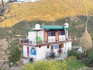 a small house with a green roof on a hill at Odyssey Stays Khirsu in Pauri