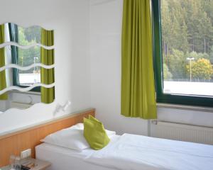 a bedroom with a bed with a green window at Motel Hirschberg in Hirschberg