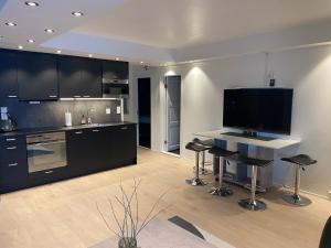 a kitchen with black cabinets and a table with stools at Arctic Seafront apartment in Kirkenes