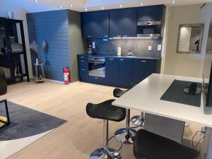 a kitchen with blue cabinets and a white table and chairs at Arctic Seafront apartment in Kirkenes