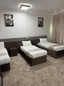 una habitación con tres camas en una habitación en Maysan Al Janubia Hotel, en Al ‘Azīzīyah