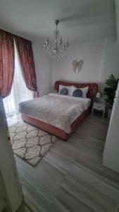 a bedroom with a large bed and a chandelier at Lux apartament in Focşani