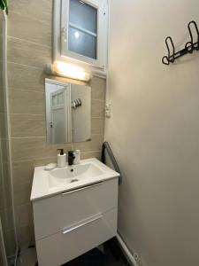 une salle de bain avec un lavabo blanc et un miroir dans l'établissement Tour Eiffel Alasseur 2 Paris, à Paris