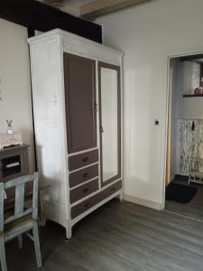 a cabinet with a mirror and a chair in a room at La Chaumière en Bellevue in Muzillac