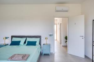 a white bedroom with a large bed with blue pillows at Stanza doppia vicino ospedale di Tricase - Palazzo Credaro in Tutino