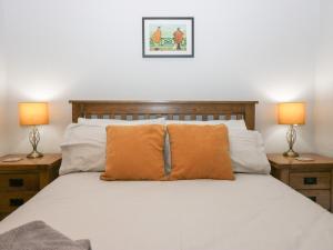 a bedroom with a bed with orange pillows and two lamps at Lady Barn in Grange Over Sands