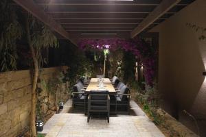 a long dining table with chairs and purple flowers at Voyage Itlalat Resort منتجع وشاليهات فوياج اطلالات in Al ‘Uyaynah