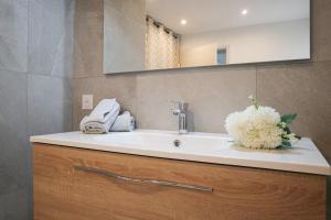 a bathroom sink with a vase of white flowers on it at Plaisir partagé Apartment in Huningue +29 photos