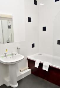 a white bathroom with a sink and a bath tub at Bowood Park Hotel in Camelford