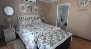 a bedroom with a bed and a clock on the wall at De Kleine Herberg in Durbanville