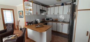 a kitchen with white cabinets and a wooden counter top at De Kleine Herberg in Durbanville +5 photos