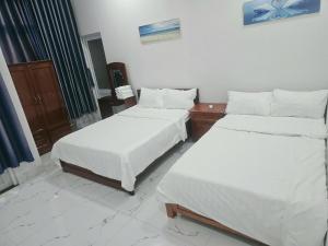 two beds in a room with white sheets at Nhà Khách Hoàng Thắng in Bồng Sơn