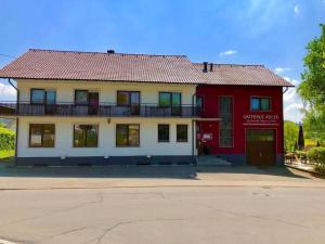 a red and white building with a balcony at Gasthaus Adler in Dietingen