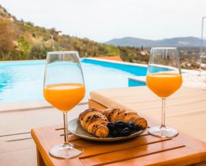 two glasses of orange juice and bread on a table at Villa La Rose in Ljubuški