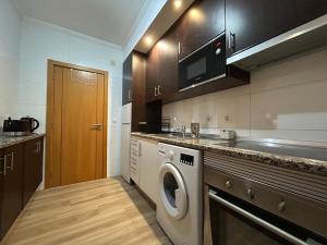 a kitchen with a washing machine and a microwave at ConVistaApartment with Pool in Portimão