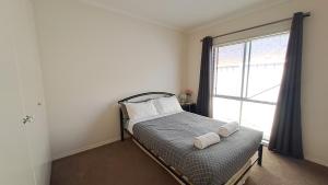 a bedroom with a bed with two pillows and a window at Cozy comfortable House in Mildura