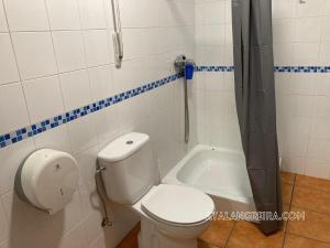 a bathroom with a toilet and a bath tub at Albergue O Beque in Moaña