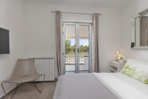 a white bedroom with a bed and a chair at Villa Lalic Gallery - Adriatic Luxury Villas in Bibinje +50 photos
