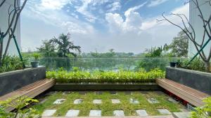 ジャカルタにある2BR Citralake Suites 2nd Floor Comfy Easy Access Apartment By Travelioのベンチと植物のある家のバルコニーからの眺め