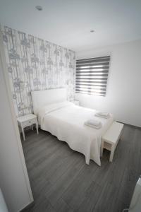 a white bedroom with a large bed and a table at Apartamento San Miguel N.3 in Jarandilla de la Vera
